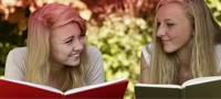 Εικόνα με δύο κοπέλες που διαβάζουν ένα βιβλίο. Η εικόνα καταδεικνύει τους πολλούς μύθους που συνδέονται με την εμμηνόρροια.